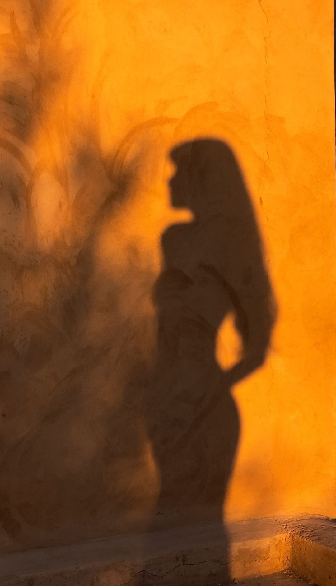 Shadow of a woman on a sunlit terracotta wall